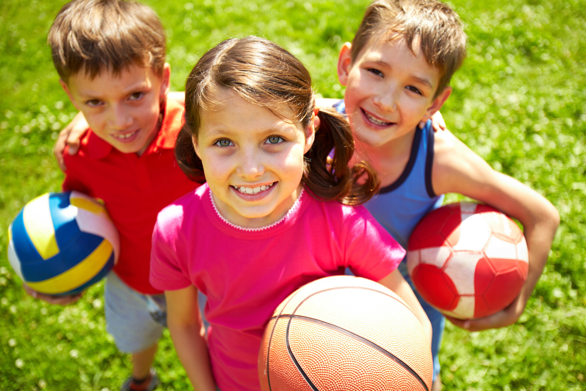 Portrait of three little children with balls looking at camera and smiling