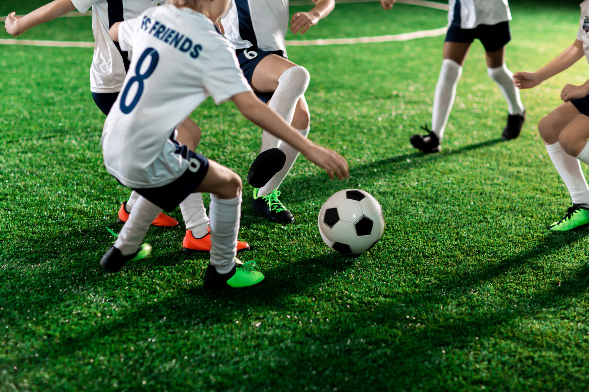 Football team of several active boys running throughout pitch after ball during game